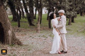 In the park of Ecuries de la Tour, Mondonville, the bride and groom stand face to face, sharing a laugh. The image is framed off-center in the woods.